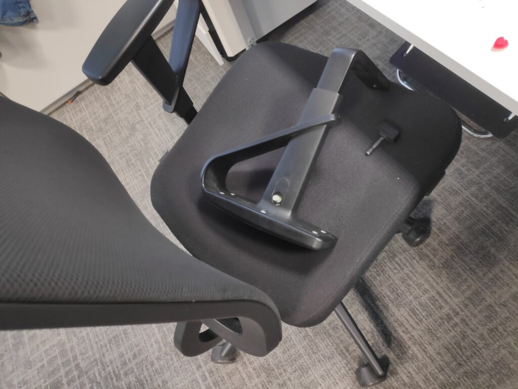 Foto de unha cadeira de oficina cun dos reposabrazos quitado.