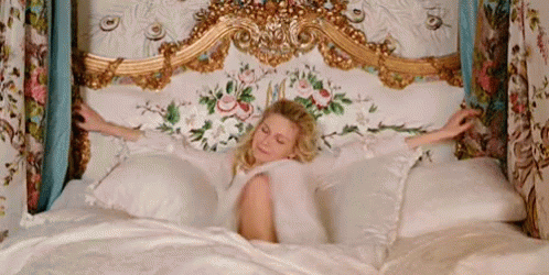 Kirsten Dunst como Marie Antoinette em uma cama.