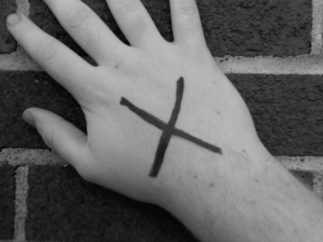 Unha man cun X negro cruzando o dorso.