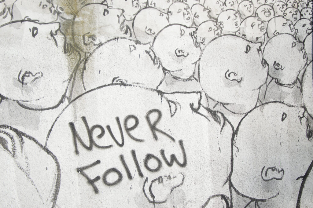 Foto dun grafiti con moitas caras que di "Never Follow".