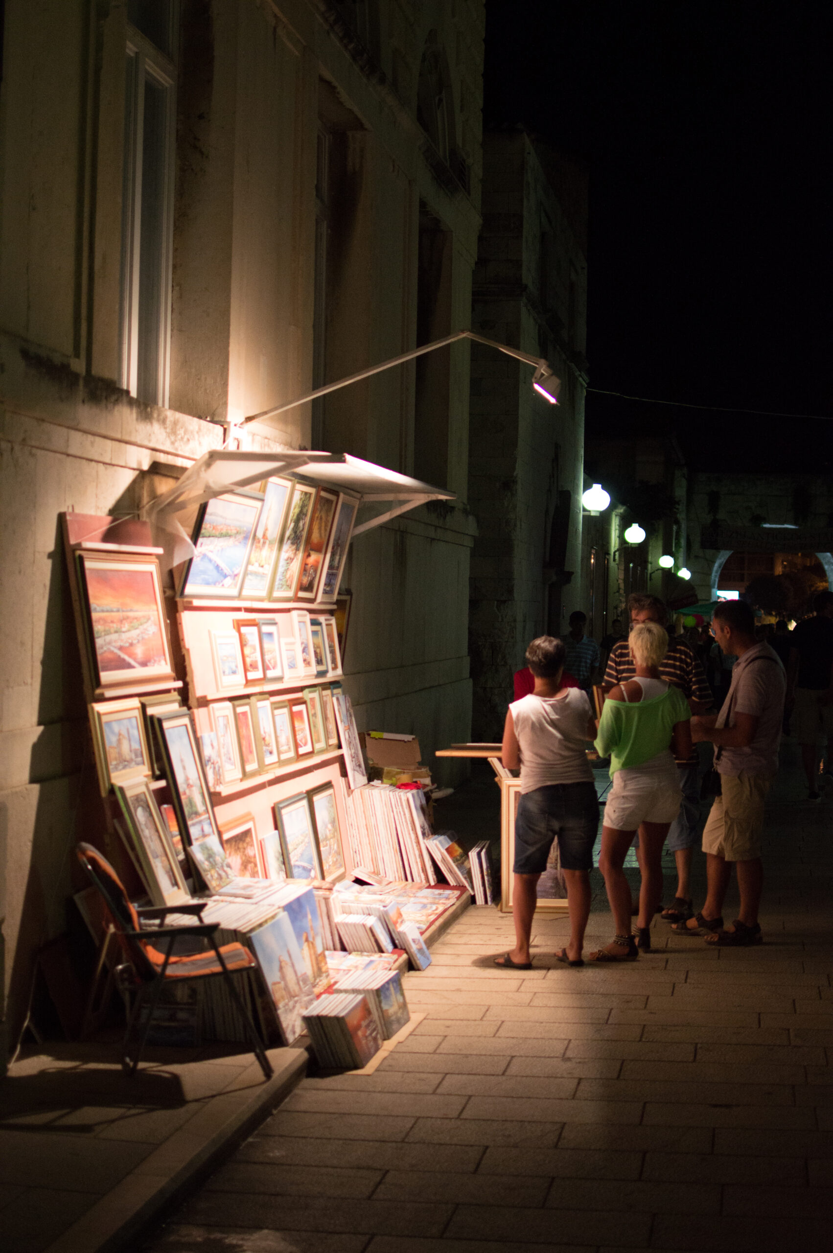 Foto dun posto de venta de cadros nunha rúa de noite.